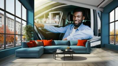 Happy young african american man driving a car on street roads Wall mural